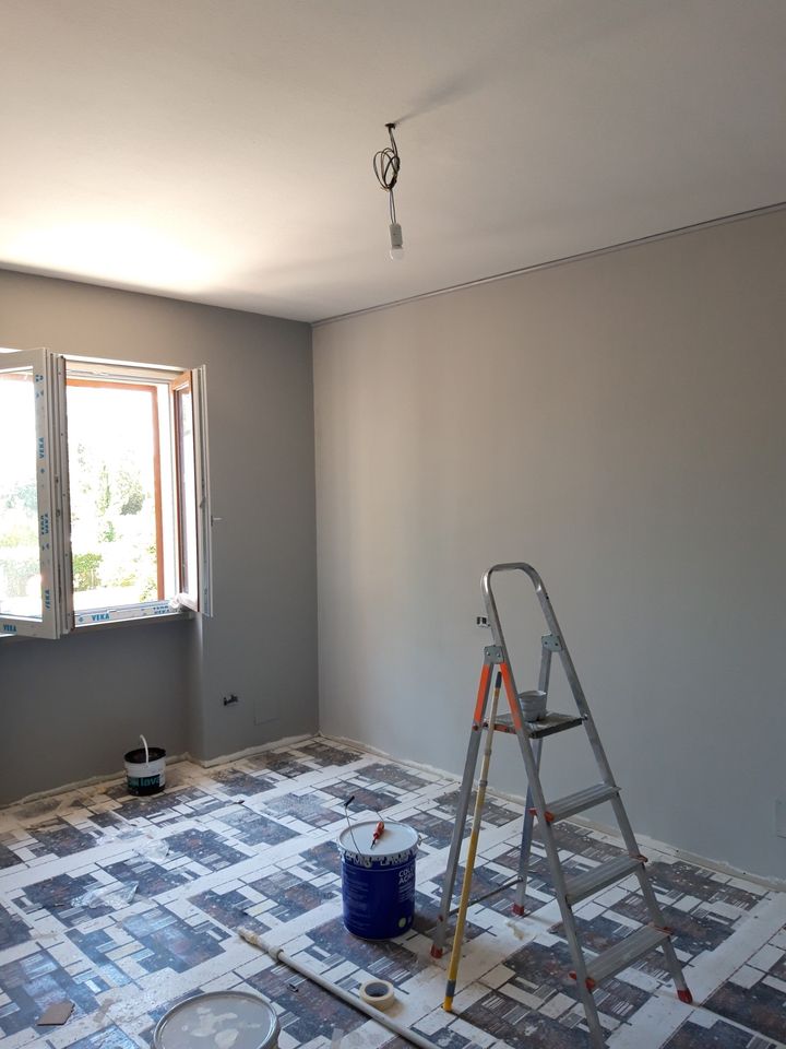 Room with grey walls during the work, ladder and protected floor